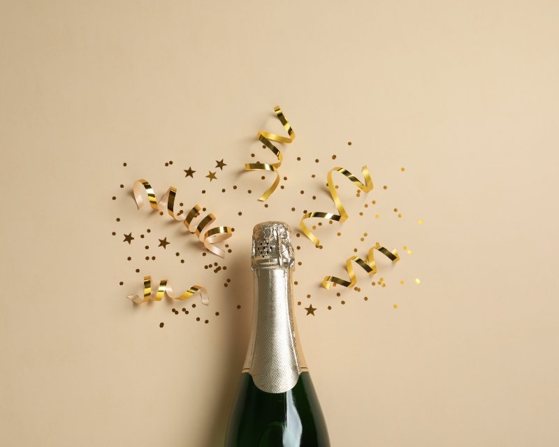 a bottle with a foil top on a blank background emanating confetti